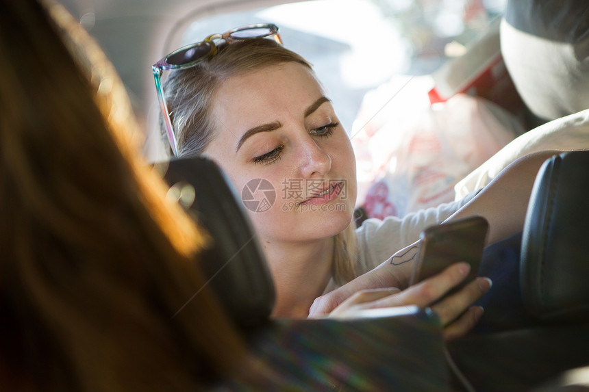 年轻妇女在车里阅读智能手机短信图片