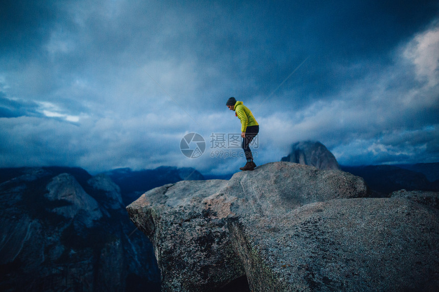 美国加利福尼亚州Yosemite公园山顶悬崖对望端的中成年男子图片