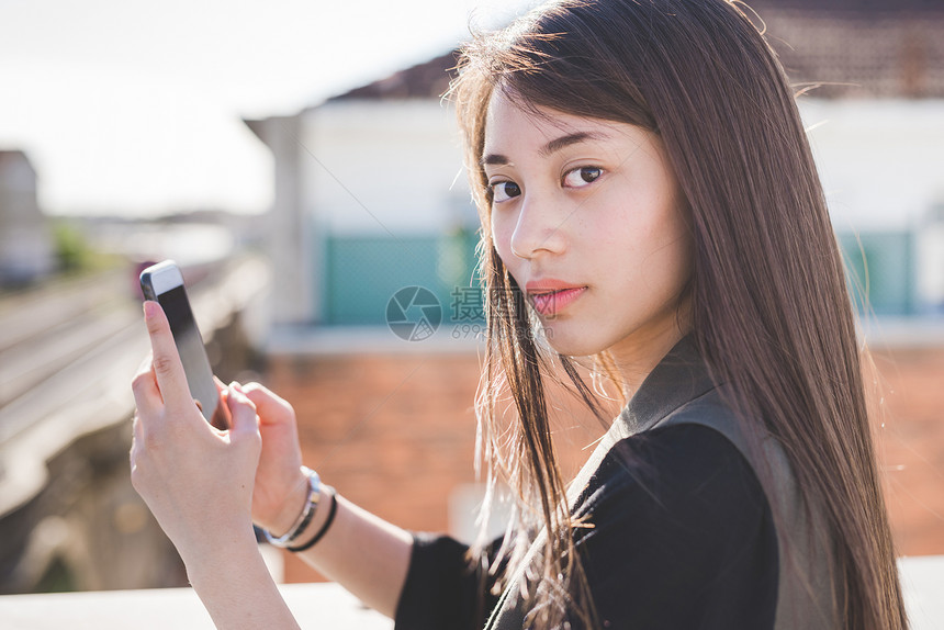 拥有智能手机的城市屋顶露台年轻女子肖像图片