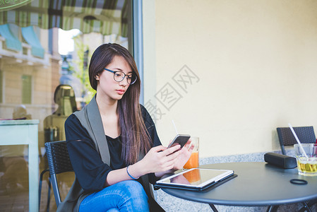 年轻妇女在人行咖啡厅阅读智能手机短信图片