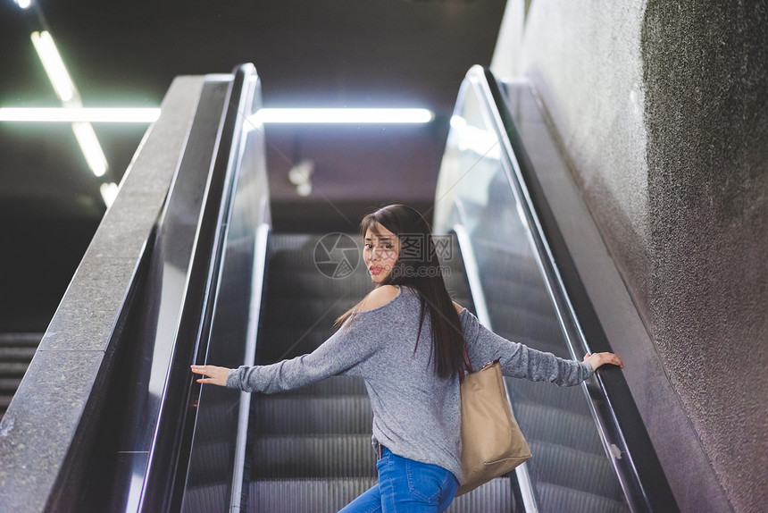 年轻女肖像站在手扶电梯回头图片