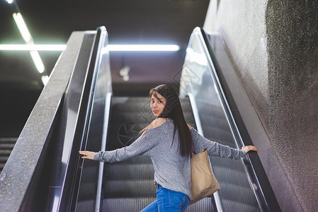 年轻女肖像站在手扶电梯回头图片