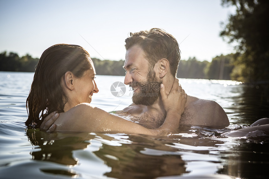 在水中面对面拥抱微笑的情侣图片