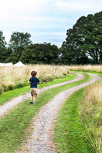 草土在泥土路上奔跑的男孩背景