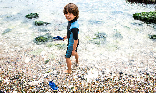 男孩赤脚走在海滩上高清图片