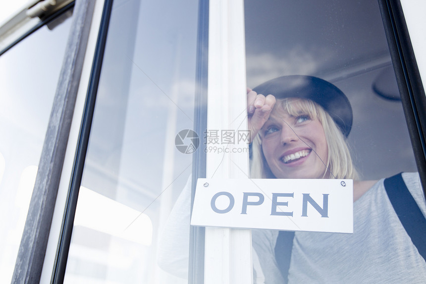 妇女微笑着依靠在玻璃门上图片