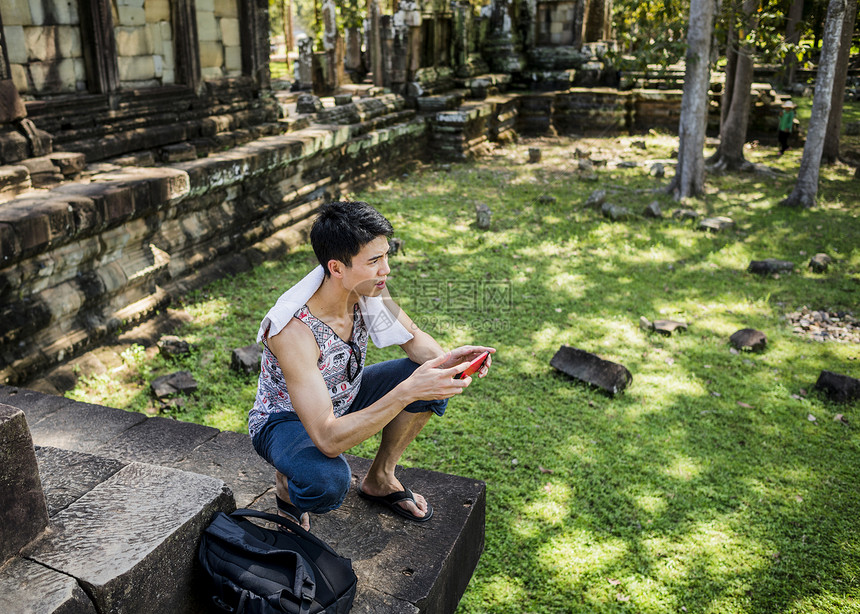 柬埔寨暹粒吴哥窟寺院玩手机的男人图片