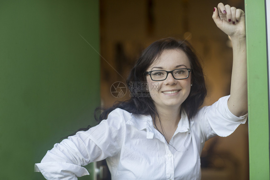 女人的肖像仰靠墙壁看着镜头微笑图片