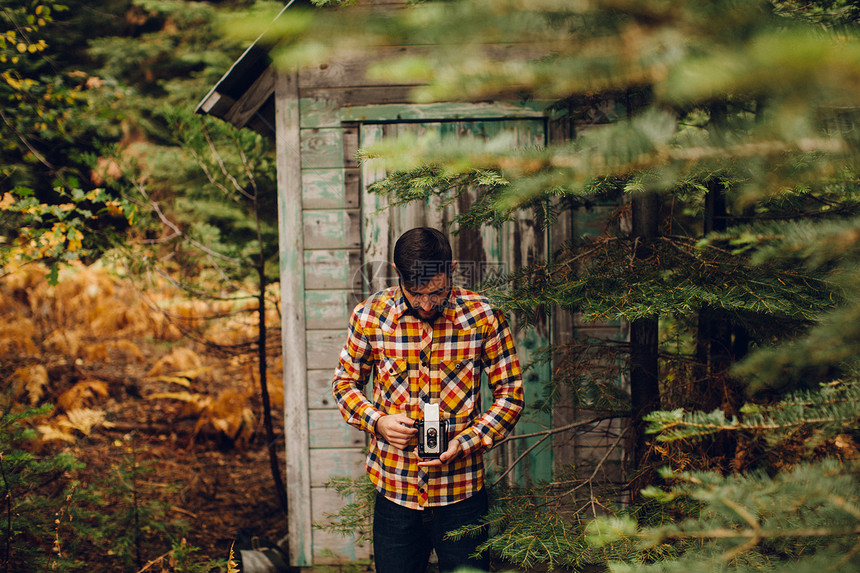 美国加利福尼亚州Shaver湖附近的林中小木屋附近青年男子用照相机拍摄片图片