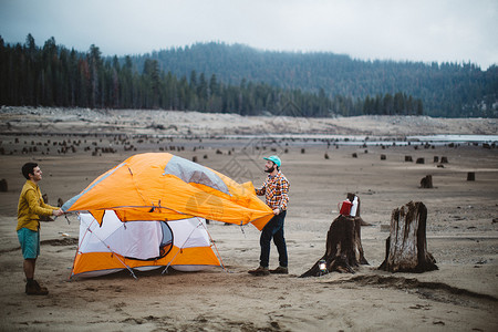 两个年轻人在美国加利福尼亚州亨廷顿湖海滩搭帐篷图片