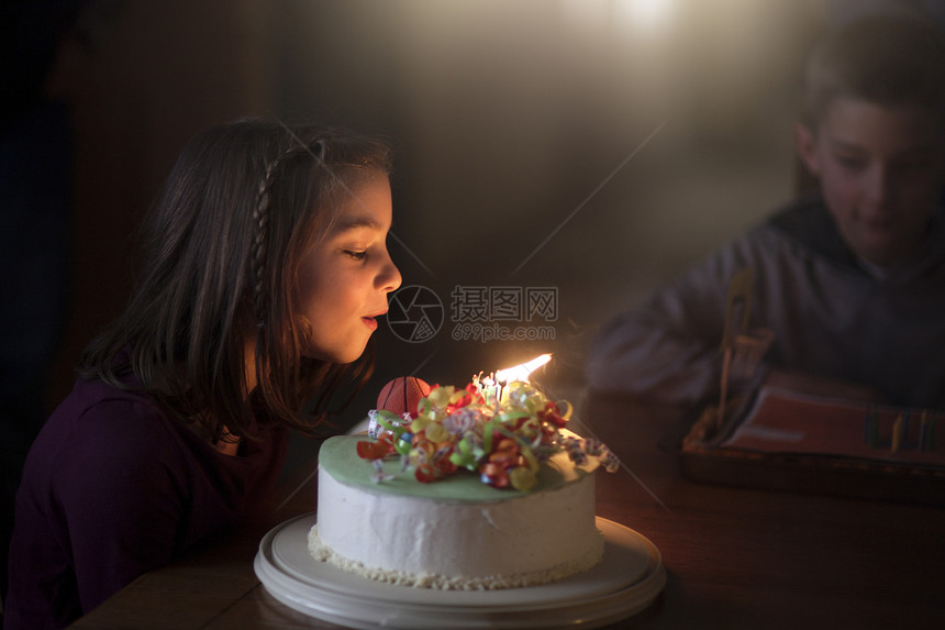 女孩在生日蛋糕上吹蜡烛图片