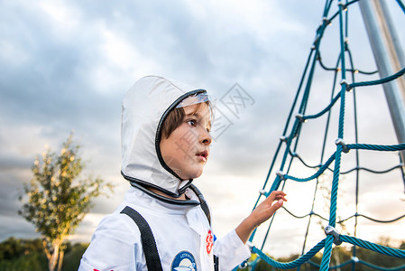 穿着宇航员服装的男孩在操场攀爬框架向外看图片