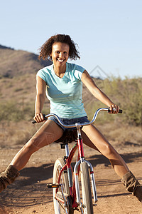年轻女子在沙漠骑着自行车微笑图片