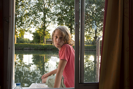 男孩坐在驳船边透过窗户看图片