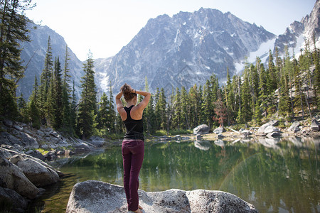 站在湖边岩石上的年轻女子看着风景高山湖大荒野美国华盛顿图片