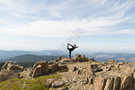 美国华盛顿银星山站在岩石上做瑜伽姿势的年轻女子图片