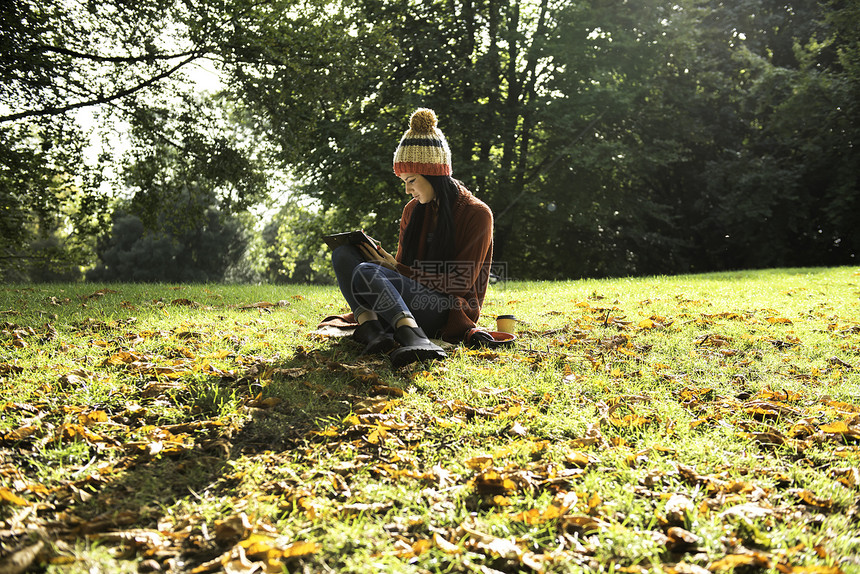 坐在公园草上学习的年轻女子图片