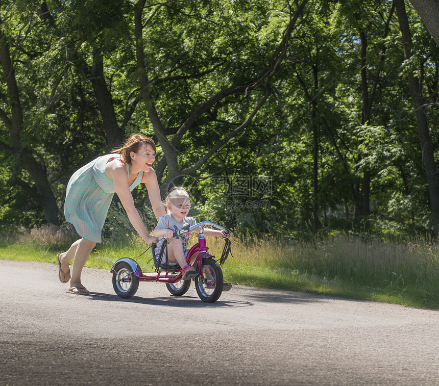 母亲推着女儿骑三轮车图片