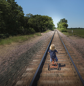 在废弃铁轨上骑三轮车的男孩图片