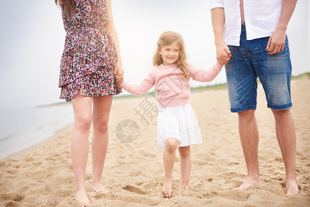 一家三口在海滩上手牵手步行图片