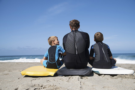 父亲教两个儿子冲浪背景图片