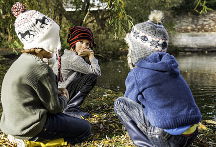 三个小男孩户外蹲在湖边图片