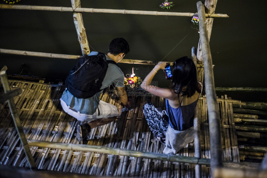 泰国清迈洛伊克拉通元宵节期间清迈一对年轻男女在平河边沿着平河放着漂浮的灯笼图片