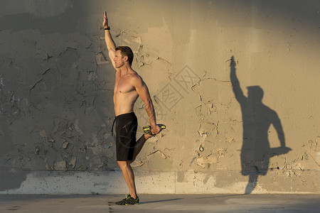 男运动员在水泥墙前伸展图片