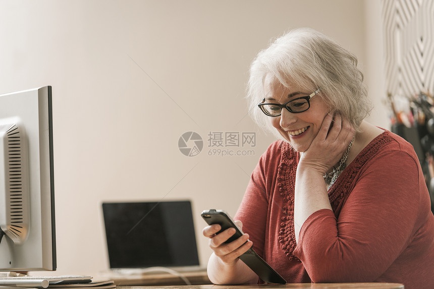 妇女微笑在工作台使用手机图片