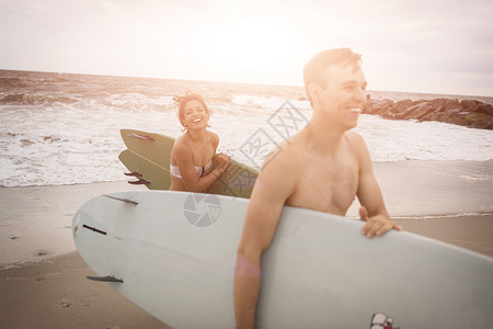 在美国纽约州罗卡韦海滩携带冲浪板的年轻夫妇图片