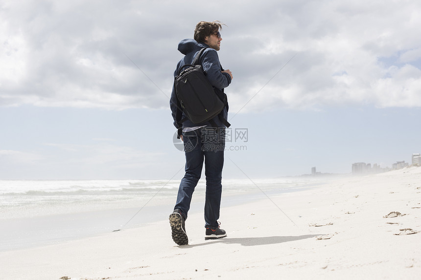 南非西开普海滩上独自漫步的年轻男子近视图片