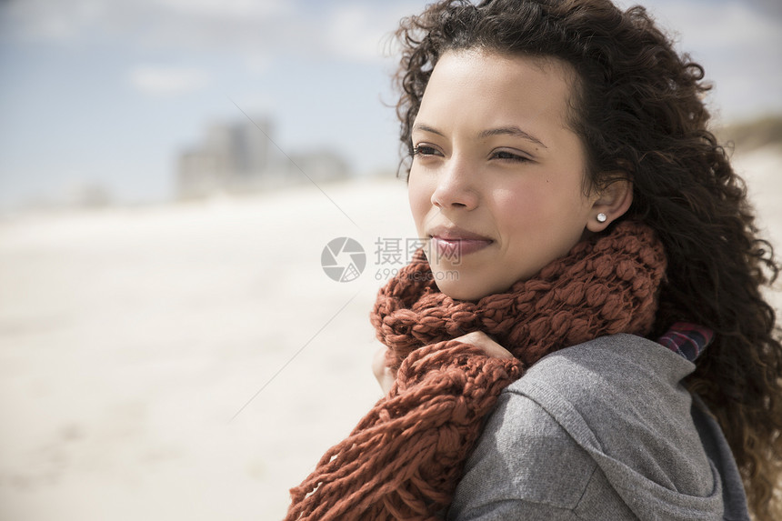围着巾的年轻女从南非西开普的海滩向外看望图片