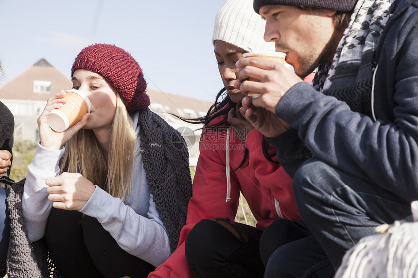南非西开普年轻成人朋友在海滩上蹲沙喝着外送咖啡图片
