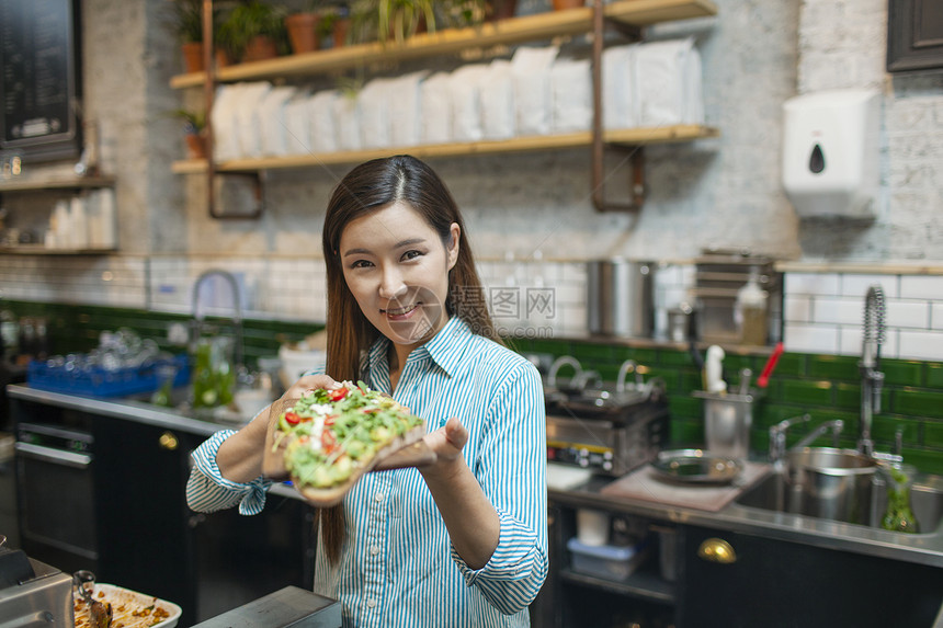 女服务员在咖啡馆里拿着开放三明治的肖像图片