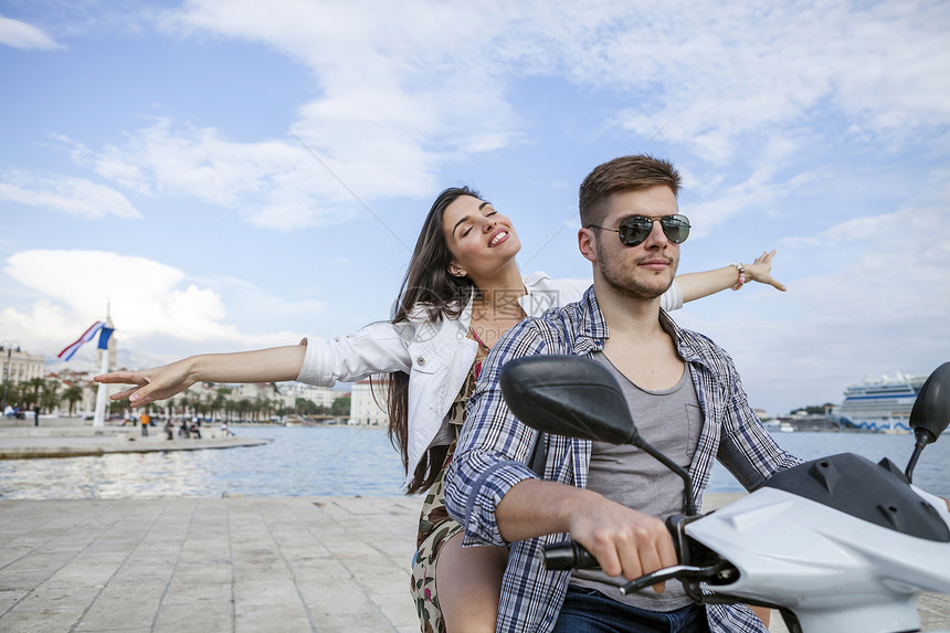 在克罗地亚达尔马提斯普利特达尔马提亚的港口骑摩托车年轻夫妇图片