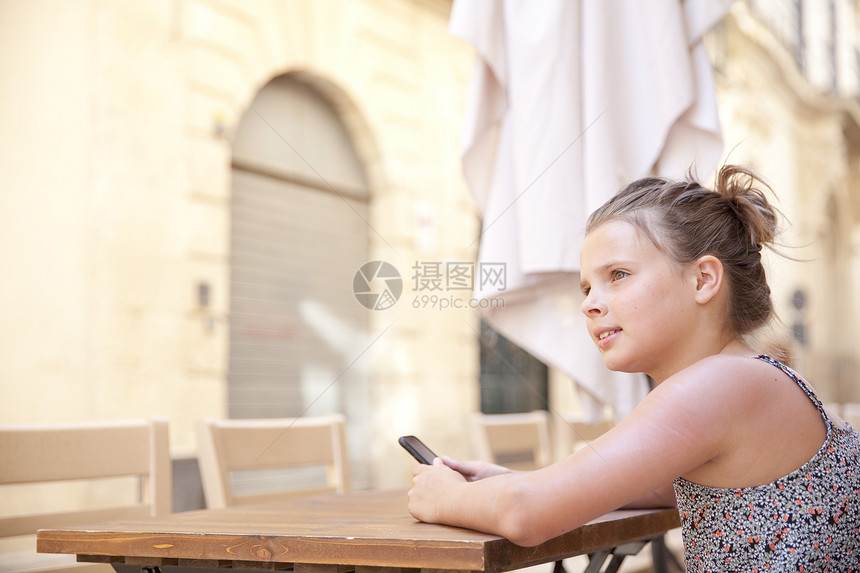 在意大利莱克餐桌上使用移动电话的年轻女孩图片