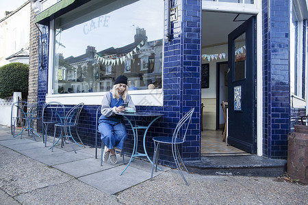 坐在咖啡厅外使用智能手机的年轻女性图片