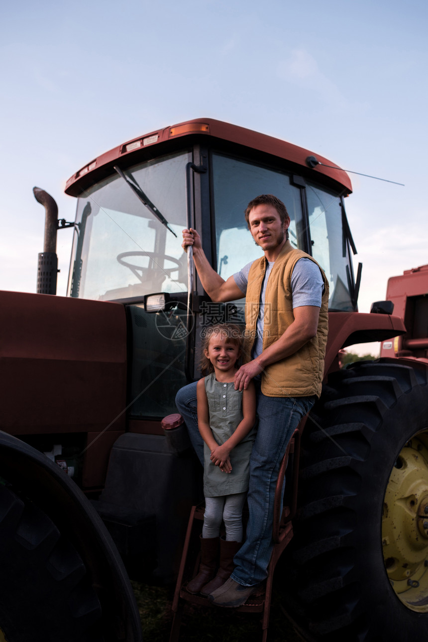 父亲和女儿在拖拉机旁边的肖像图片