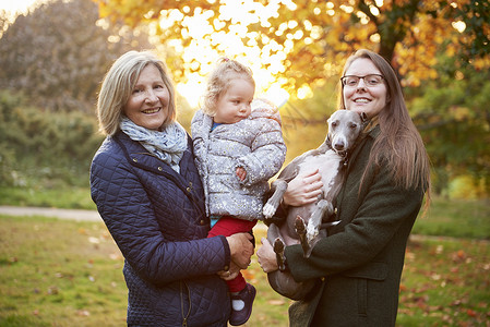 秋天公园抱着女孩的老年妇女和抱着狗的女生的肖像图片
