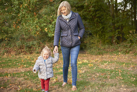 在秋天公园和孙女一起散步的老人图片