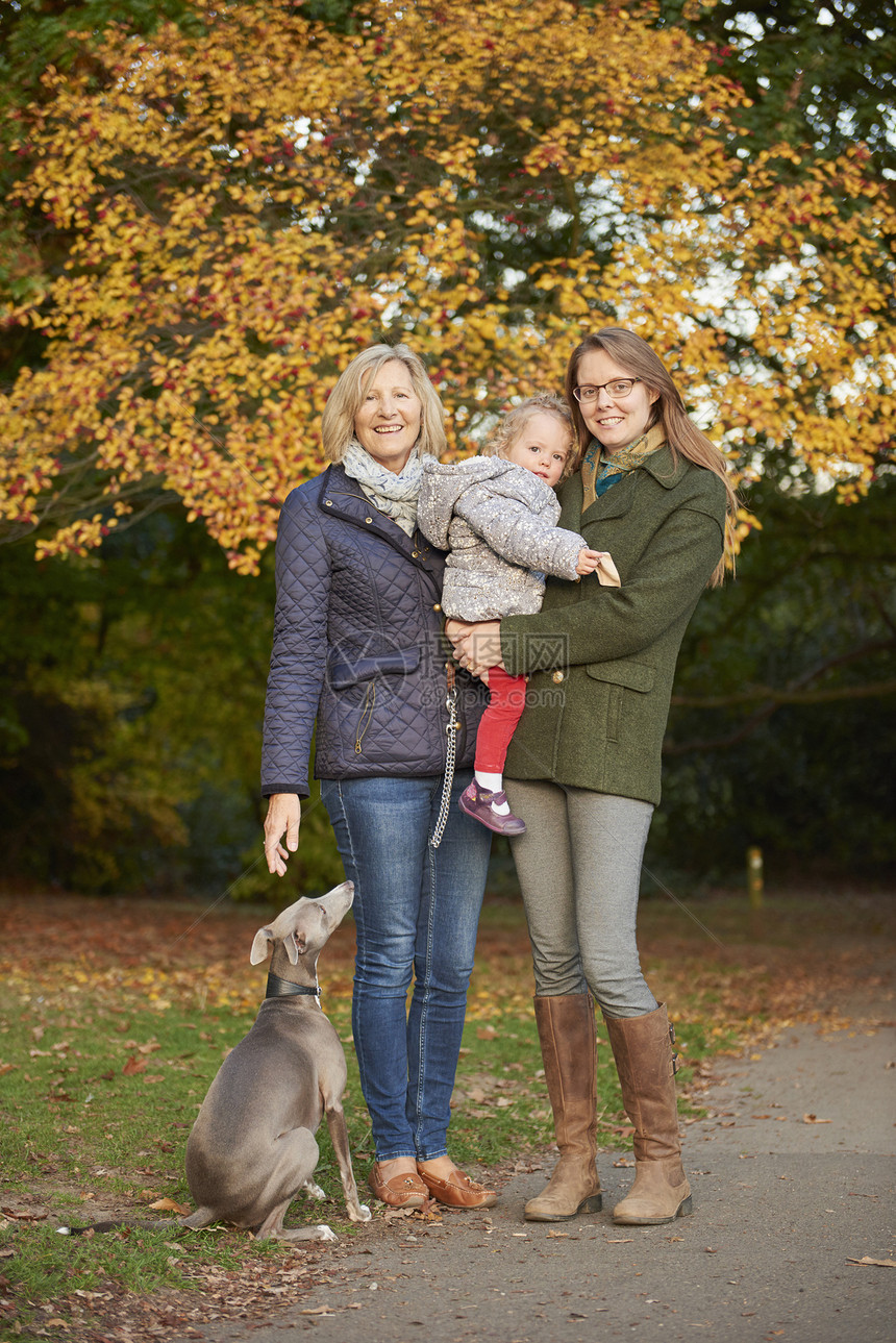 秋天公园里妇女抱着女儿和妈妈与宠物狗的肖像图片