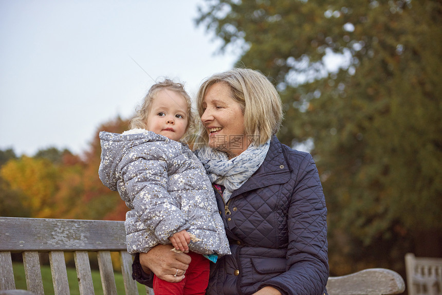 在秋天公园和孙女坐在一起的高级女子图片
