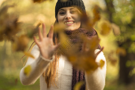 年轻女子将秋叶扔在空气中微笑着容图片