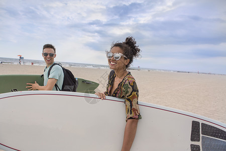 在美国纽约州罗卡韦海滩携带冲浪板的年轻夫妇高清图片