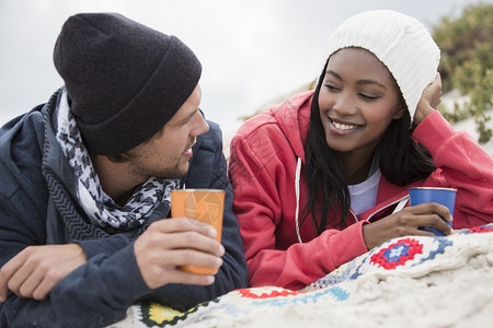 在南非西开普海滩上野餐和聊天的年轻夫妇图片