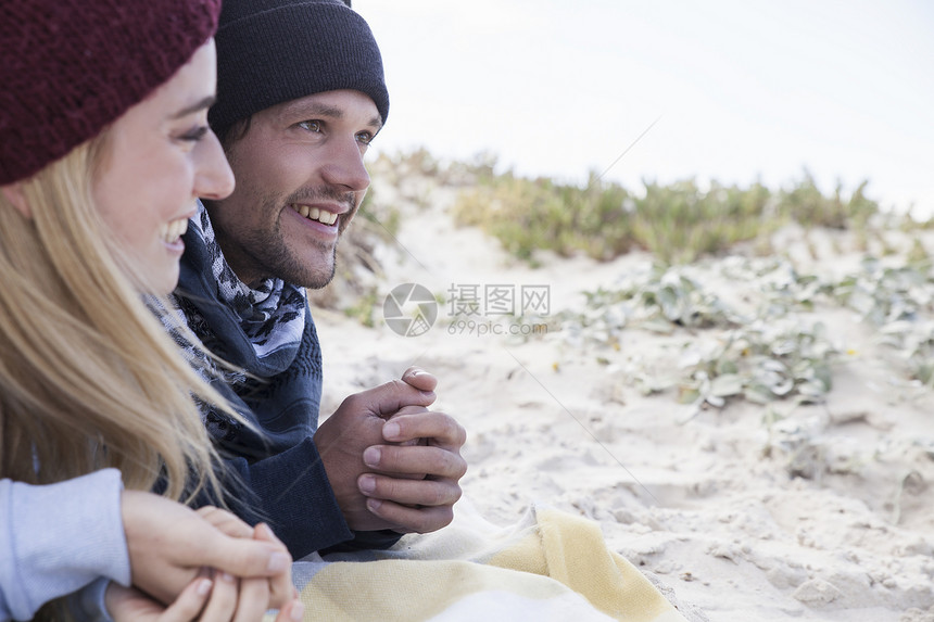 在南非西开普的海滩躺在野餐毯上的年轻夫妇图片