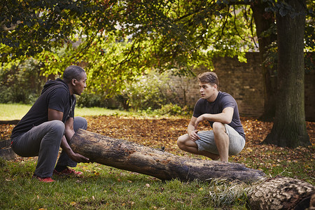 在公园里一个男人教另一个男人如何抬树干图片