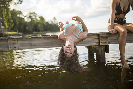 海滩一名年轻女子躺在码头上垂着湿漉漉的长发图片