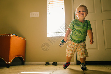 男孩在室内行走一只脚鞋和手拿着鞋图片