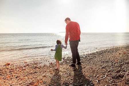 父亲和女儿站在沙滩上牵手图片